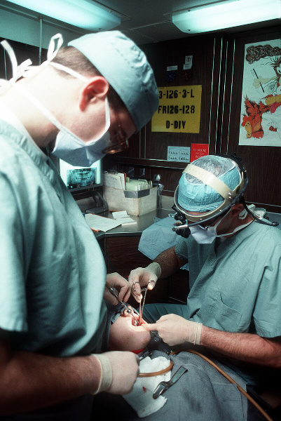 Two dental surgeons working on a patient's teeth.