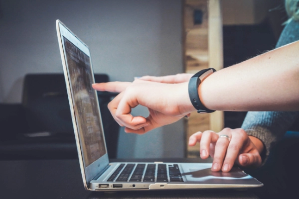 Two people point at the screen of a laptop.