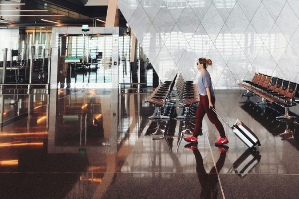 Woman pulling a suitcase through an airport.