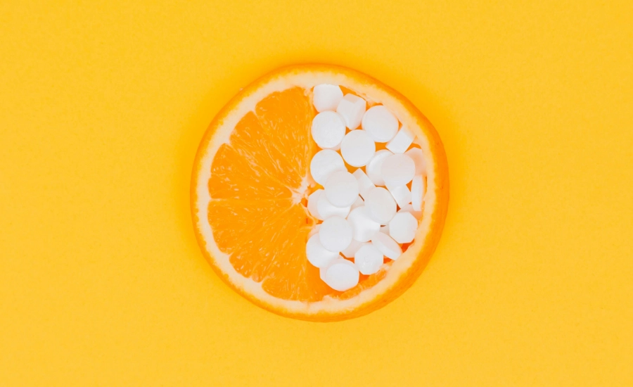 An orange sliced in half, with one quarter showing orange segments the other showing tablets.